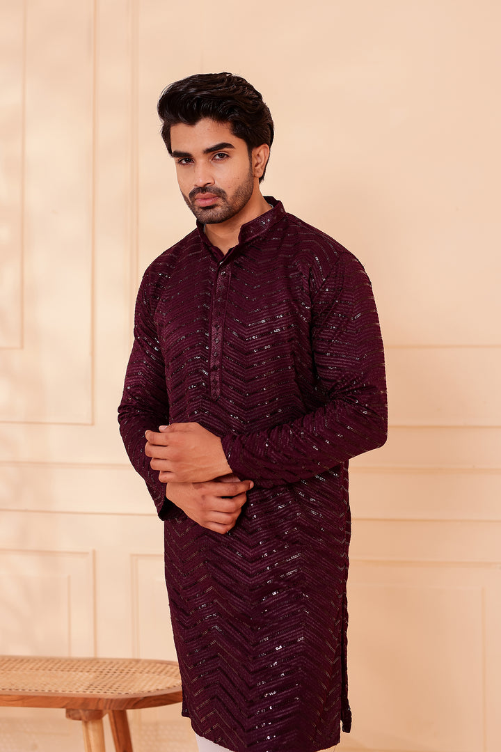 Man wearing a maroon kurta against a beige backgrou